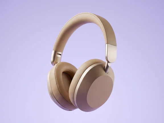 Aubrel One headphones in warm sand and brushed aluminium, three-quarter view on a soft lavender background